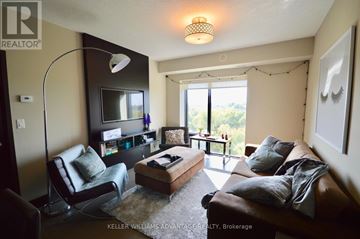 London East (East B) condo for rent - A living room with a brown couch and a black chair.