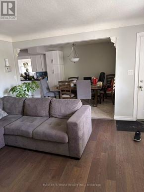 St. Catharines (E. Chester) apartment for rent - A grey couch sits in a living room with a dining area in the background.