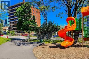 Hamilton condo for rent - A playground with a bright orange slide in the foreground and a multi-story building in the background.