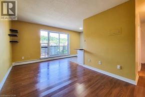 Hamilton condo for rent - A room with wooden floors and a window overlooking a parking lot.