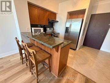 Toronto (Willowdale East) condo for rent - A kitchen with a table and chairs in front of a refrigerator.