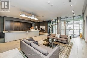 Toronto (Waterfront Communities) condo for rent - A spacious living room with a grey sofa and a glass door leading to a balcony.