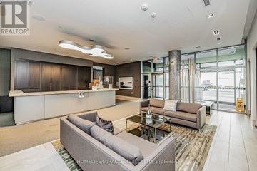 Toronto (Waterfront Communities) condo for rent - A spacious living room with a grey sofa and a glass door leading to a balcony.