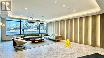 Toronto (Banbury-Don Mills) condo for rent - A living room with a couch, chair, and a table with a yellow sign on it.