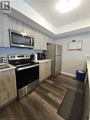 Kitchener townhouse for rent - A kitchen with a stove top oven, microwave, and refrigerator.