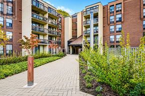 Toronto (Willowdale East) condo for rent - A brick building with a balcony and a small garden in front.