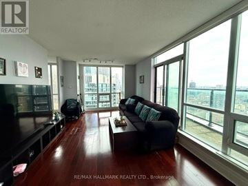 Toronto (Waterfront Communities) condo for rent - A living room with a black couch and a wooden floor.