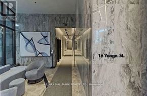 Toronto (Waterfront Communities) condo for rent - A hallway with a marble wall and a chair in front of a RE/MAX sign.