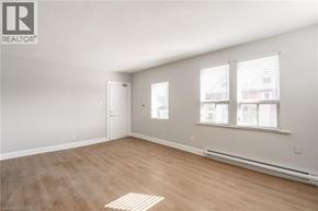 Hamilton apartment for rent - A room with a door, two windows, and a wooden floor.