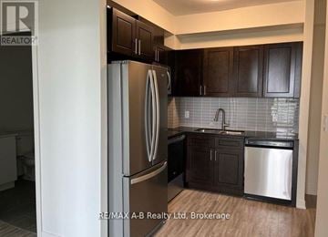 Waterloo condo for rent - A kitchen with a stainless steel refrigerator and dark brown cabinets.