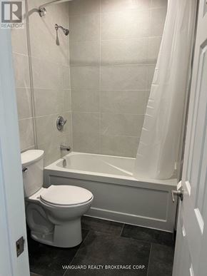 Toronto (Oakwood Village) townhouse for rent - A white toilet sits next to a bathtub in a bathroom.