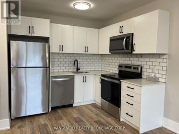 Toronto (Oakwood Village) townhouse for rent - A kitchen with white cabinets and a black fridge.