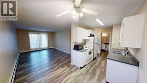 Grande Prairie apartment for rent - A well-lit, spacious kitchen and living area with wood flooring and white appliances.