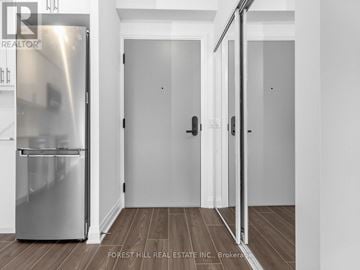 Toronto (Bathurst Manor) condo for rent - A stainless steel refrigerator in a kitchen with white walls and wooden flooring.