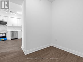 Toronto (Bathurst Manor) condo for rent - A white room with a wood floor and a wall with a Forest Hill Real Estate Inc. logo.