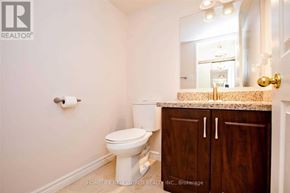 Toronto (Steeles) condo for rent - A white toilet sits in a bathroom with a wooden cabinet and a mirror above the sink.