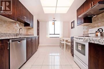 Toronto (Steeles) condo for rent - A kitchen with dark wood cabinets and white appliances.