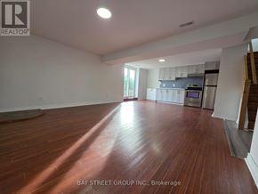 Oshawa (Donevan) apartment for rent - A spacious room with wooden flooring and a kitchen area in the background.