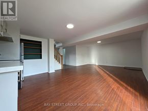 Oshawa (Donevan) apartment for rent - A spacious room with wooden flooring and white walls.
