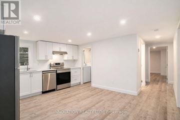 Ottawa duplex for rent - A spacious kitchen with white cabinets and a wooden floor.