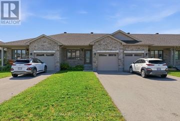Mississippi Mills townhouse for rent - Two cars are parked in front of a brick house with a sign that says REALTOR.