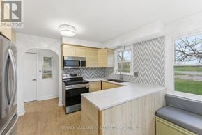 Fort Erie (Ridgeway) apartment for rent - A kitchen with a refrigerator, microwave, oven, and a window with a view of the outside.