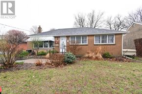 Oshawa (Centennial) apartment for rent - A house with a brown brick exterior and a white door is surrounded by a grassy area and some shrubbery.