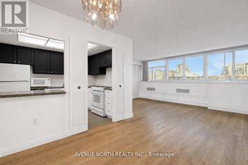 Ottawa condo for rent - A large, empty room with a kitchen area and a chandelier.