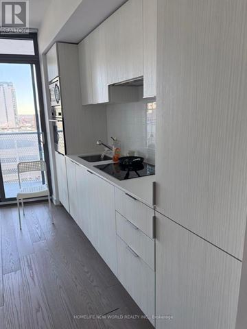 Toronto (Bay Street Corridor) condo for rent - A modern kitchen with white cabinets and a view of the city.