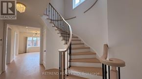 Vaughan (Patterson) apartment for rent - A staircase with a wooden handrail and a beige carpeted runner leads up to a landing with a window and a chandelier.