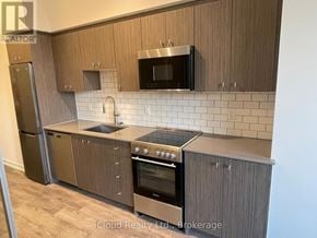Kitchener condo for rent - A kitchen with wooden cabinets and a stainless steel refrigerator.