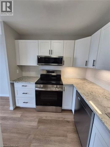 Brantford condo for rent - A kitchen with white cabinets and a granite countertop.