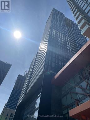 Toronto (Church-Yonge Corridor) condo for rent - A tall building with a glass facade stands under a bright sun.