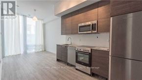 Toronto (Church-Yonge Corridor) condo for rent - A modern kitchen with stainless steel appliances and wooden cabinets.
