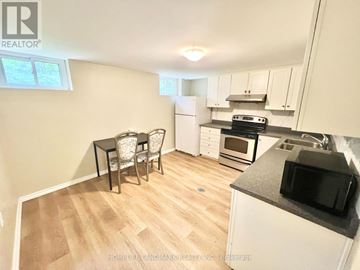 Toronto (Bathurst Manor) apartment for rent - A kitchen with a table and chairs in the foreground and a refrigerator, microwave, oven, and stove in the background.