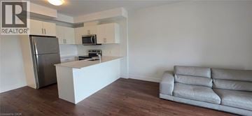 Kitchener condo for rent - A white kitchen with a refrigerator and a couch.