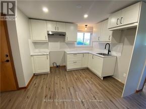Port Colborne (Main Street) apartment for rent - A kitchen with white cabinets and a wooden floor.