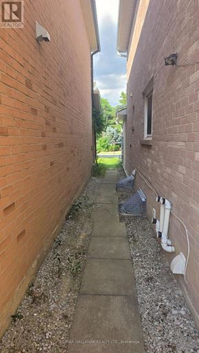 Vaughan (Brownridge) apartment for rent - A narrow alley with a concrete path and brick walls on either side.