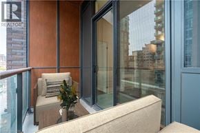 Burlington condo for rent - A balcony with a couch, pillow, and a vase with flowers.