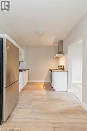 Brantford apartment for rent - A kitchen with a refrigerator on the left and a stove on the right.