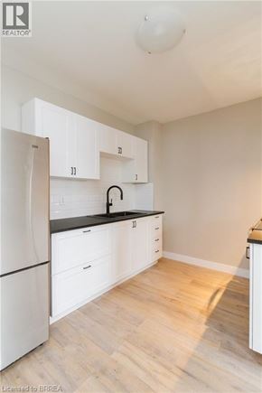 Brantford apartment for rent - A kitchen with white cabinets and a black countertop.