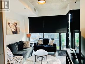 Toronto (Stonegate-Queensway) condo for rent - A living room with a black couch, a grey couch, a white coffee table, and a large window with a view of the city.