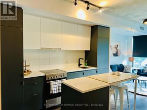 Toronto (Stonegate-Queensway) condo for rent - A modern kitchen with white and black cabinetry and a central island.