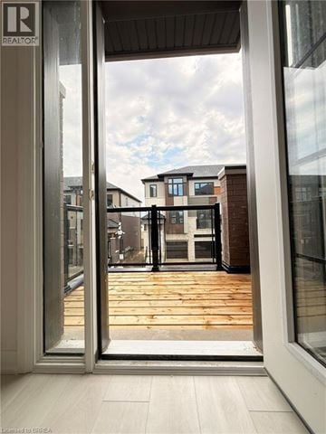 Brantford townhouse for rent - A view from inside a building looking out through a glass door at a residential area.