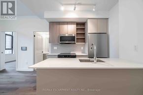 Burlington (Brant) condo for rent - A modern kitchen with a refrigerator, microwave, and oven.