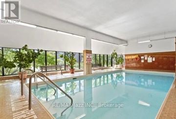 Oshawa (O'neill) condo for rent - A large indoor swimming pool with a glass wall on one side.