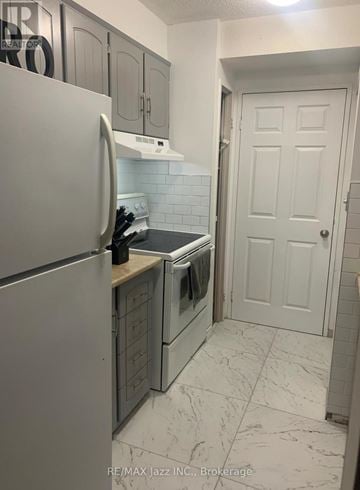Oshawa (O'neill) condo for rent - A kitchen with a white refrigerator and a white door.