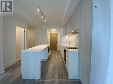 Toronto (Church-Yonge Corridor) condo for rent - A modern kitchen with white cabinets and a wooden island.