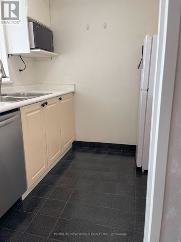 Toronto (Woburn) condo for rent - A small kitchen with a white fridge and a microwave above the sink.