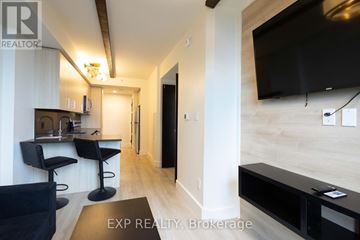 Waterloo condo for rent - A modern living room with black furniture and a flat screen TV mounted on the wall.
